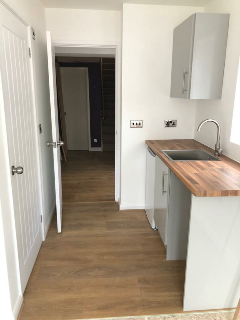 Utility room with a wooden worktop, inset sink and grey units