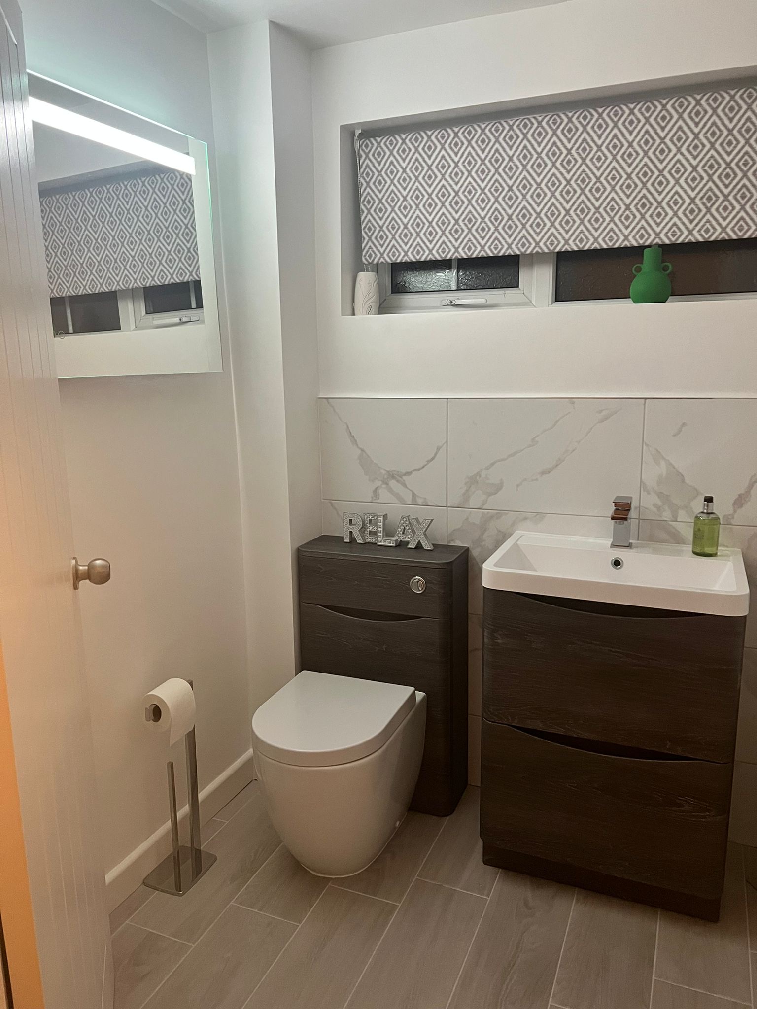 Back-to-wall toilet, vanity unit and LED mirror in a tiled bathroom